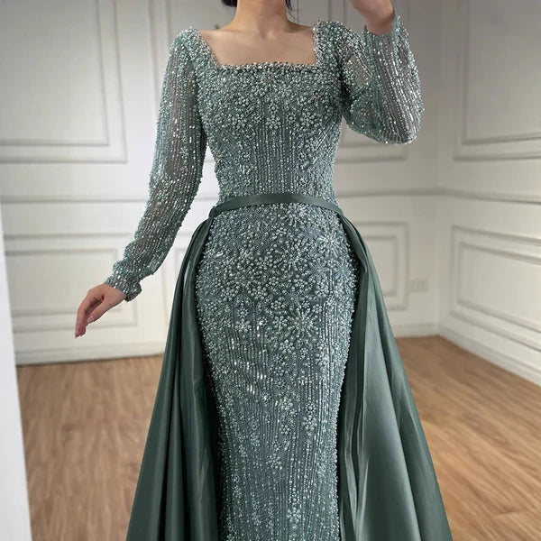 Green evening gown with long sleeves and beaded details in a room with wooden floor and white paneled wallsElegant silver evening gown with long sleeves and a train, reflected in a mirror. Beaded, long train, silk, floor length, formal, dress, champagne colour, cream, beige, nude, skin colour, dubai style, middle east, muslim, old-money, classic, luxury, video, sparkle, glitter, real photos, 