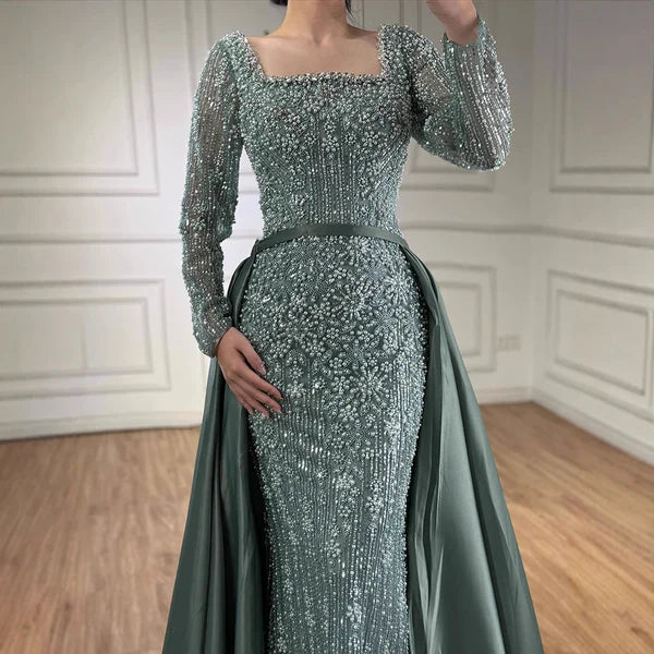 Green evening gown with long sleeves and sequin detailing in a room with wooden floor and white paneled walls.Elegant silver evening gown with long sleeves and a train, reflected in a mirror. Beaded, long train, silk, floor length, formal, dress, champagne colour, cream, beige, nude, skin colour, dubai style, middle east, muslim, old-money, classic, luxury, video, sparkle, glitter, real photos,#2026 #bestonlineshop #missuniverse #besteveninggown #numberone #bestquality #top #eveningdress #mostpopular #cockt