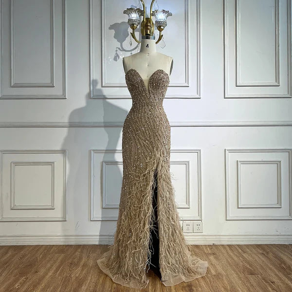 Woman wearing   formal evening gown  dress with a slit,intricate beading, beige nude skin, feathered bottom, evening gown with a high slit, glitter sparkling diamonds, sweetheart neckline  v-neck, mermaid, train, old-money classy elegant dubai style, saudi arabic, sleeveless, elliesaab, prom, wedding guest, bridesmaid, mother of the bride, christmas, luxury, celebrity, expensive cheap, vintage, real photos, high-end, chooseone, viral, where to buy, now, shop, store, miss universe, best, number one top