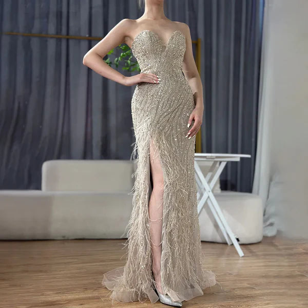 Woman wearing  champagne formal evening gown  dress with a slit intricate beading, beige nude feathered bottom, evening gown with a high slit, glitter sparkling diamonds, sweetheart neckline  v-neck, mermaid, train, old-money classy elegant dubai style, saudi arabic, sleeveless, elliesaab, prom, wedding guest, bridesmaid, mother of the bride, christmas, luxury, celebrity, expensive cheap, vintage, real photos, high-end, chooseone, viral, where to buy, now, shop, store, miss universe, best, number one top