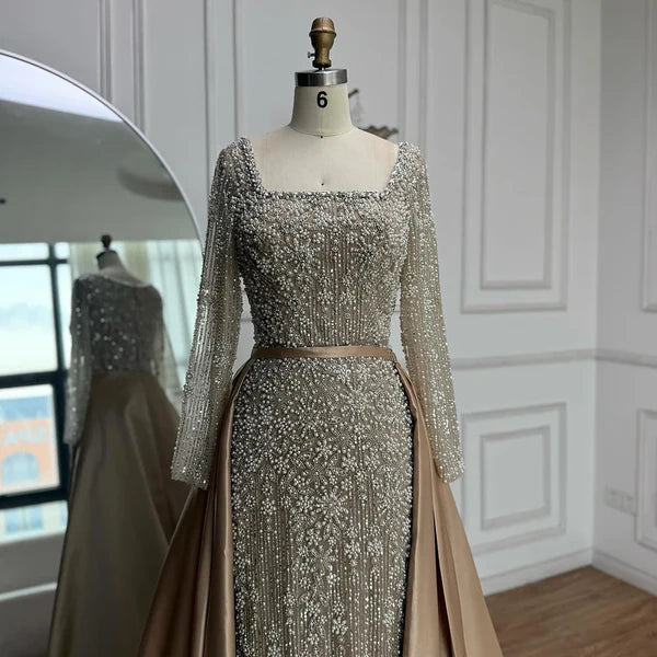 Elegant silver evening gown with long sleeves and a train, reflected in a mirror. Beaded, long train, silk, floor length, formal, dress, champagne colour, cream, beige, nude, skin colour, dubai style, middle east, muslim, 