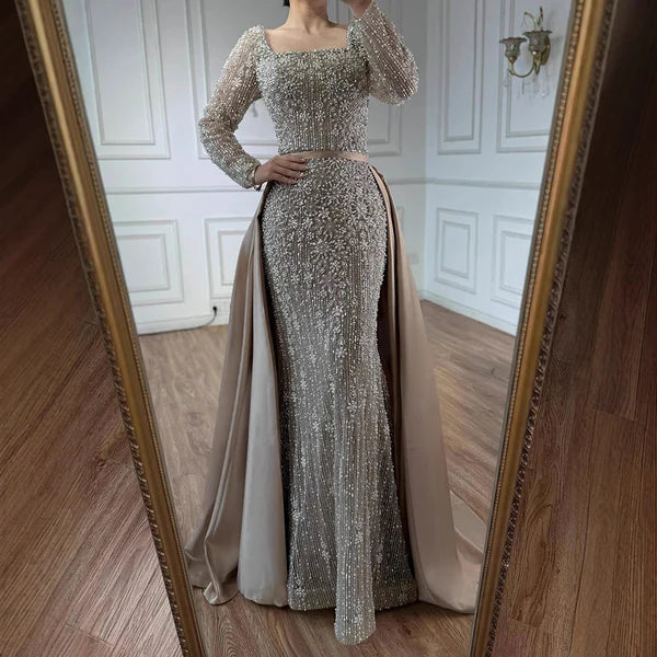 Elegant silver evening gown with long sleeves and a train, reflected in a mirror. Beaded, long train, silk, floor length, formal, dress, champagne colour, cream, beige, nude, skin colour, dubai style, middle east, muslim, old-money, classic, luxury, 