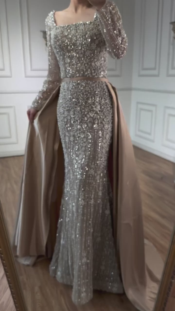 Elegant silver evening gown with long sleeves and a train, reflected in a mirror. Beaded, long train, silk, floor length, formal, dress, champagne colour, cream, beige, nude, skin colour, dubai style, middle east, muslim, old-money, classic, luxury, video, sparkle, glitter